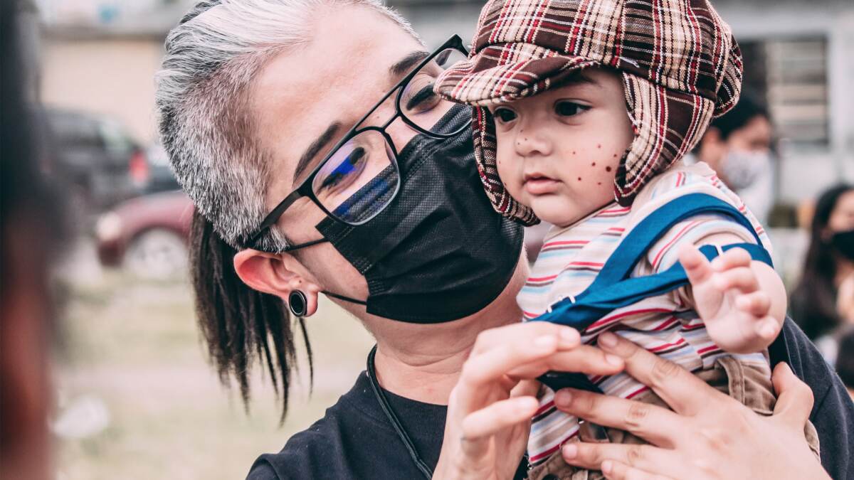 Female doctor wearing a medical mask holds a migrant child