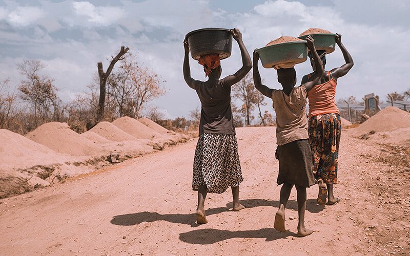 A group of African migrant women carry food in baskets on their heads
